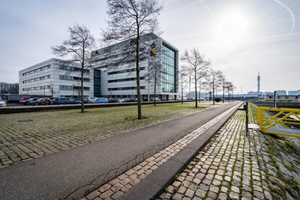 Modern kantoorgebouw aan de Waalhaven Oostzijde in Rotterdam met parkeerplaats en geplaveide wandelpaden.